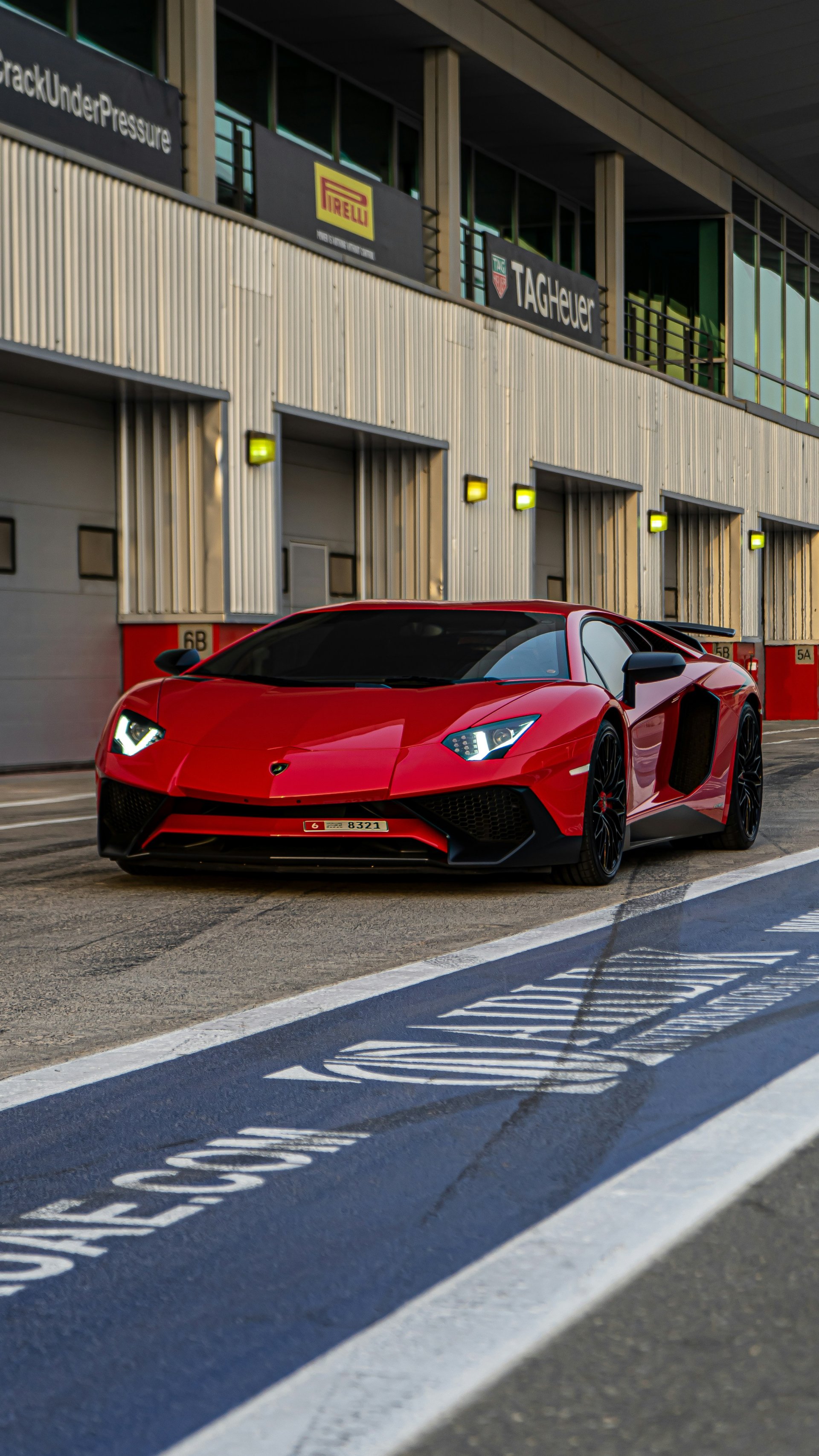 Red Lamborghini Aventador with scissor doors open at racing circuit