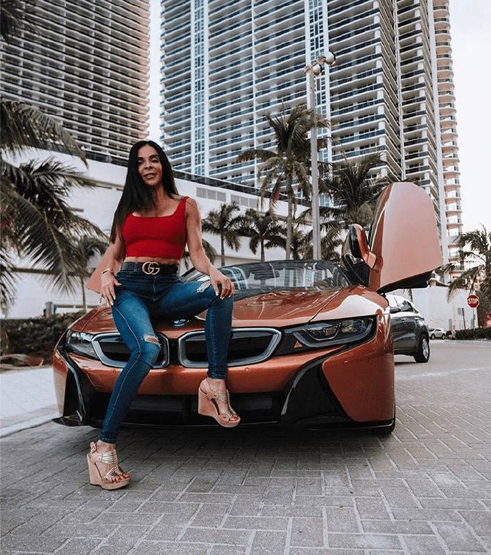 Woman in red crop top posing on copper BMW i8 with butterfly doors in Miami