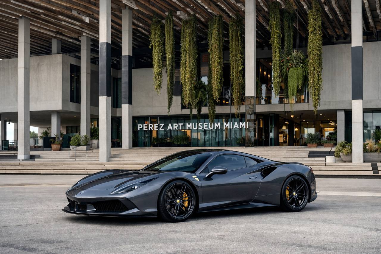 Dark gray Ferrari parked in front of modern Pérez Art Museum with hanging gardens and contemporary architecture