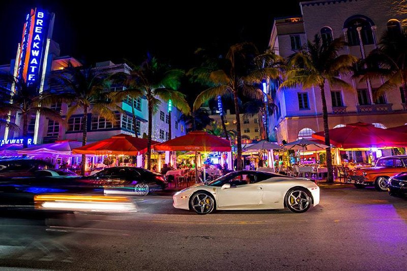 Luxury exotic car parked on Miami Ocean Drive with palm trees and beachfront